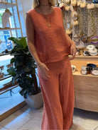 NEWYORKLISTED COMFORT COLLECTION: Person wearing an orange outfit in a store setting with decor and plants.