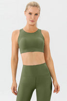 NEWYORKLISTED ACTIVEWEAR COLLECTION: Woman wearing an olive green sports bra and leggings set on a white background
