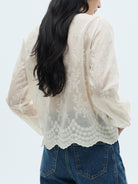 NEWYORKLISTED STYLE COLLECTION: Person wearing a white lace blouse and blue jeans on a light gray background