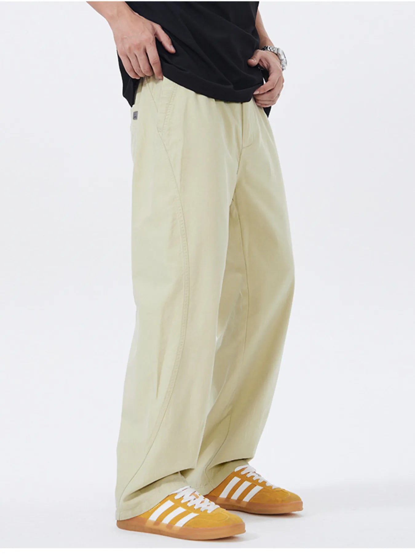 NEWYORKLISTED ATLAS MEN's COLLECTION: Person wearing beige pants and yellow shoes with white stripes on a white background
