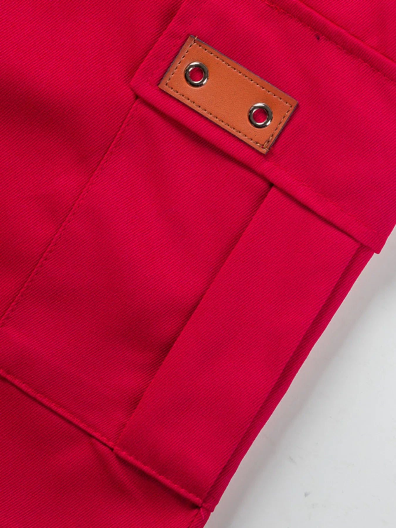 NEWYORKLISTED ATLAS MEN'S COLLECTION: Close-up of a red fabric pocket with a brown leather patch on a white background