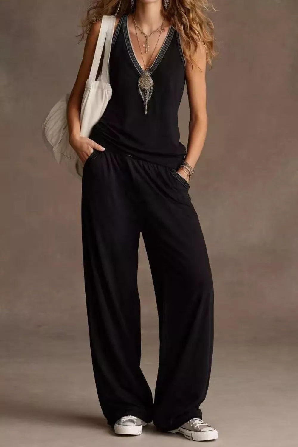 NEWYORKLISTED STYLE COLLECTION: Person wearing a black jumpsuit with a plain background