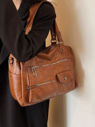 NEWYORKLISTED STYLE COLLECTION: Brown leather handbag held by a person against a neutral background
