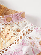 NEWYORKLISTED STYLE COLLECTION: Close-up of pink, white, and beige lace fabric on a wooden surface.