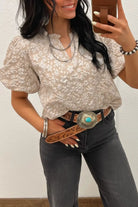 NEWYORKLISTED STYLE COLLECTION: Woman taking a mirror selfie wearing a patterned blouse and dark jeans with a belt.