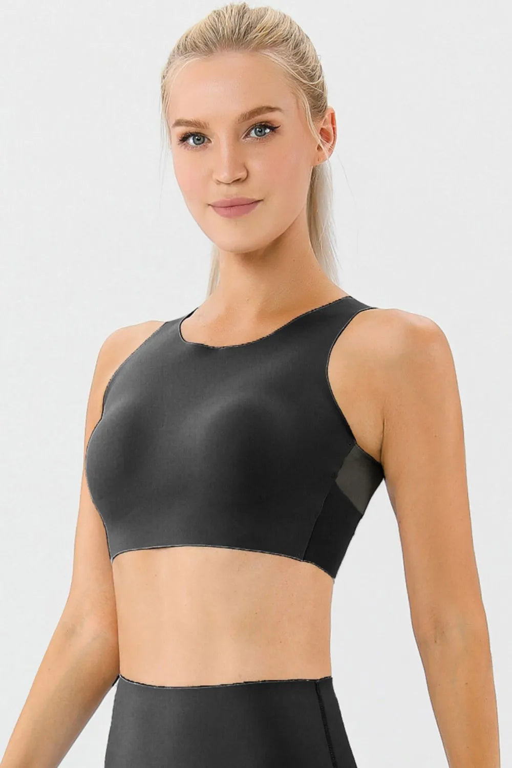 NEWYORKLISTED ACTIVEWEAR COLLECTION: Woman wearing a black sports bra against a light gray background