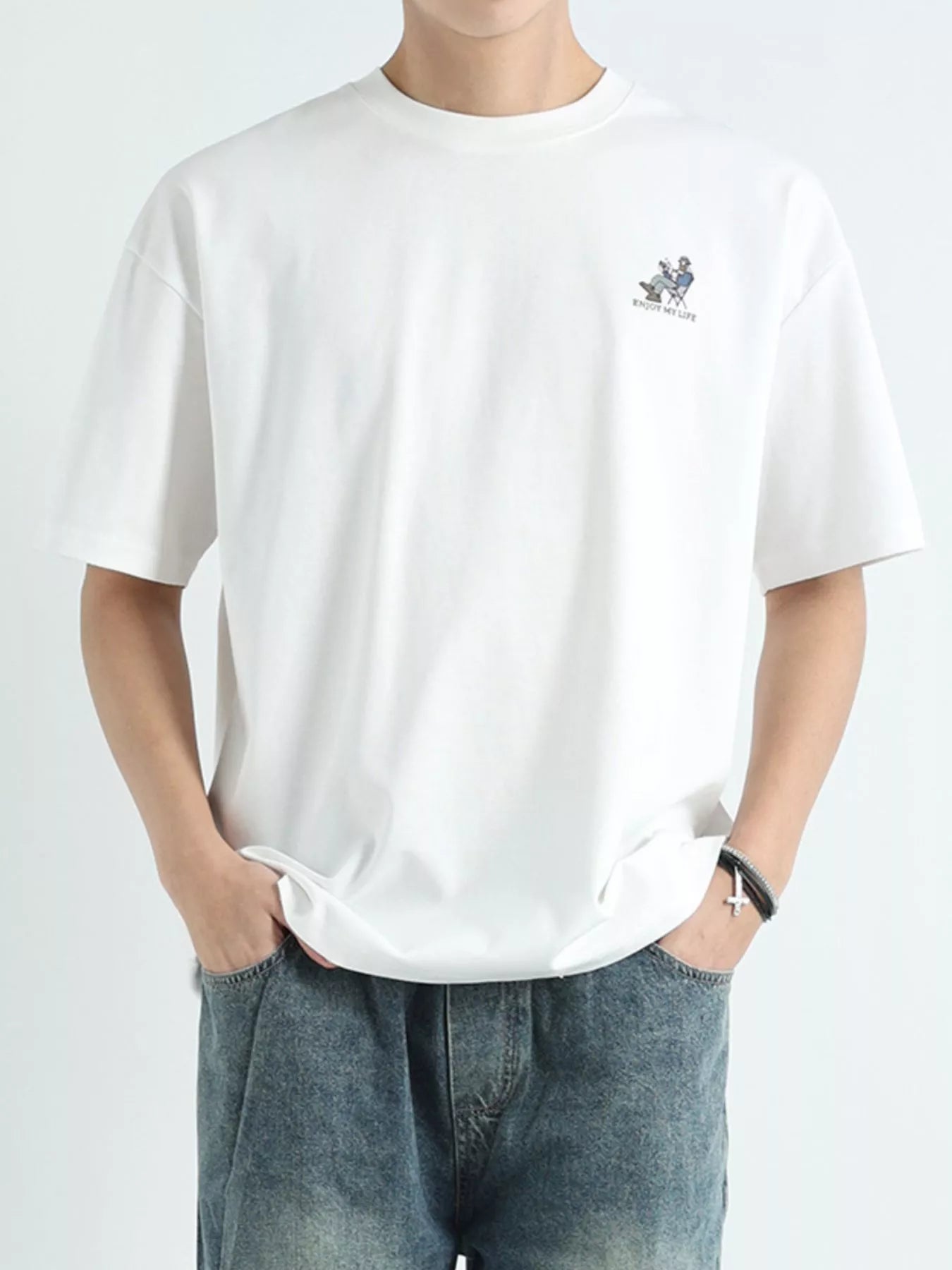 Person wearing a white t-shirt with a small logo on a plain background