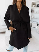 NEWYORKLISTED STYLE COLLECTIONB: Person wearing a black coat in a minimalistic room