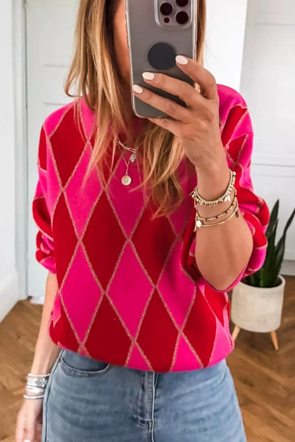 NEWYORKLISTED STYLE COLLECTION: Person wearing a pink argyle sweater taking a mirror selfie.