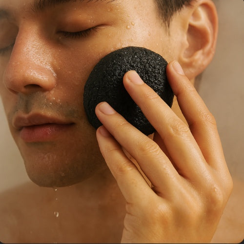 NEWYORKLISTED COSMETIC COLLECTION: Person using a black exfoliating sponge on their face with a blurred background
