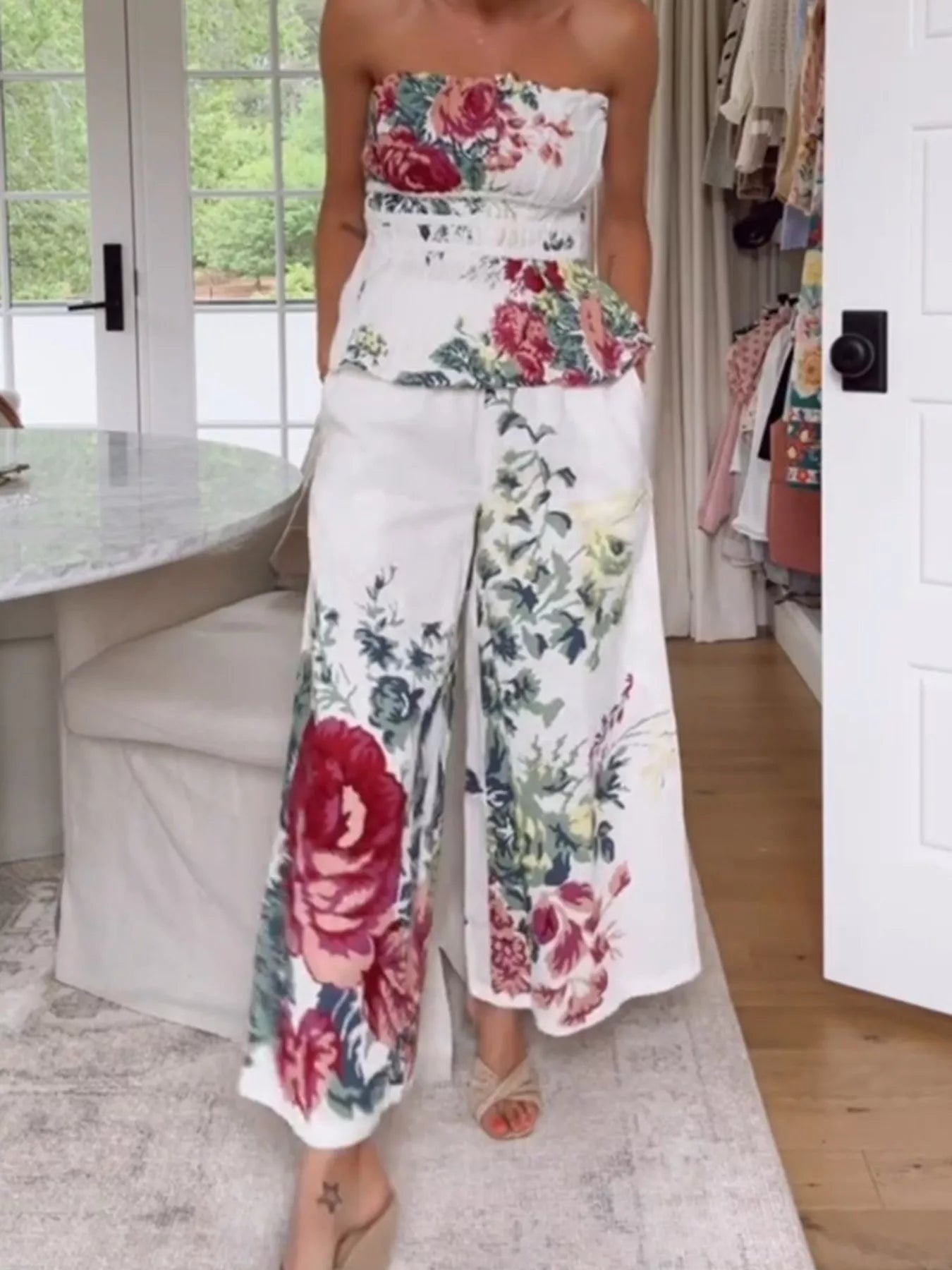 NEWYORKLISTED STYLE COLLECTION: Person wearing a floral strapless top and wide-leg pants in a home setting.