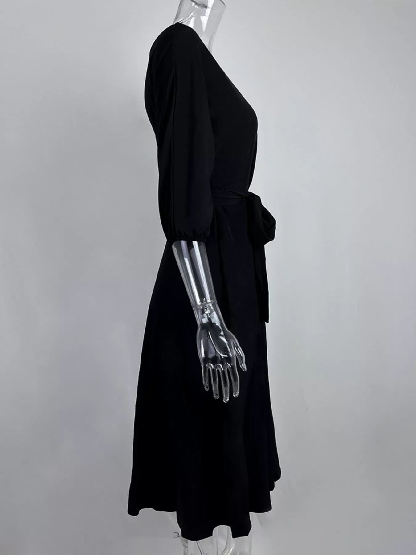 NEWYORKLISTED STYLE COLLECTION: Mannequin wearing a black dress with a metallic arm on a gray background
