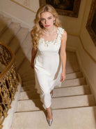 NEWYORKLISTED STYLE COLLECTION: Woman in a white dress with floral details walking down a staircase.