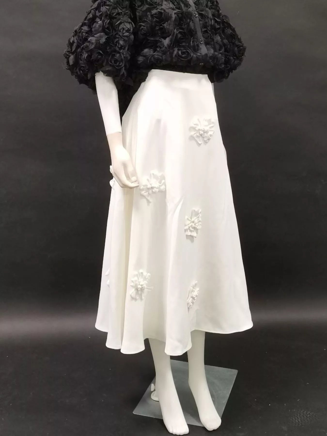 NEWYORKLISTED STYLE COLLECTION: Mannequin wearing a white dress with floral embroidery against a black background