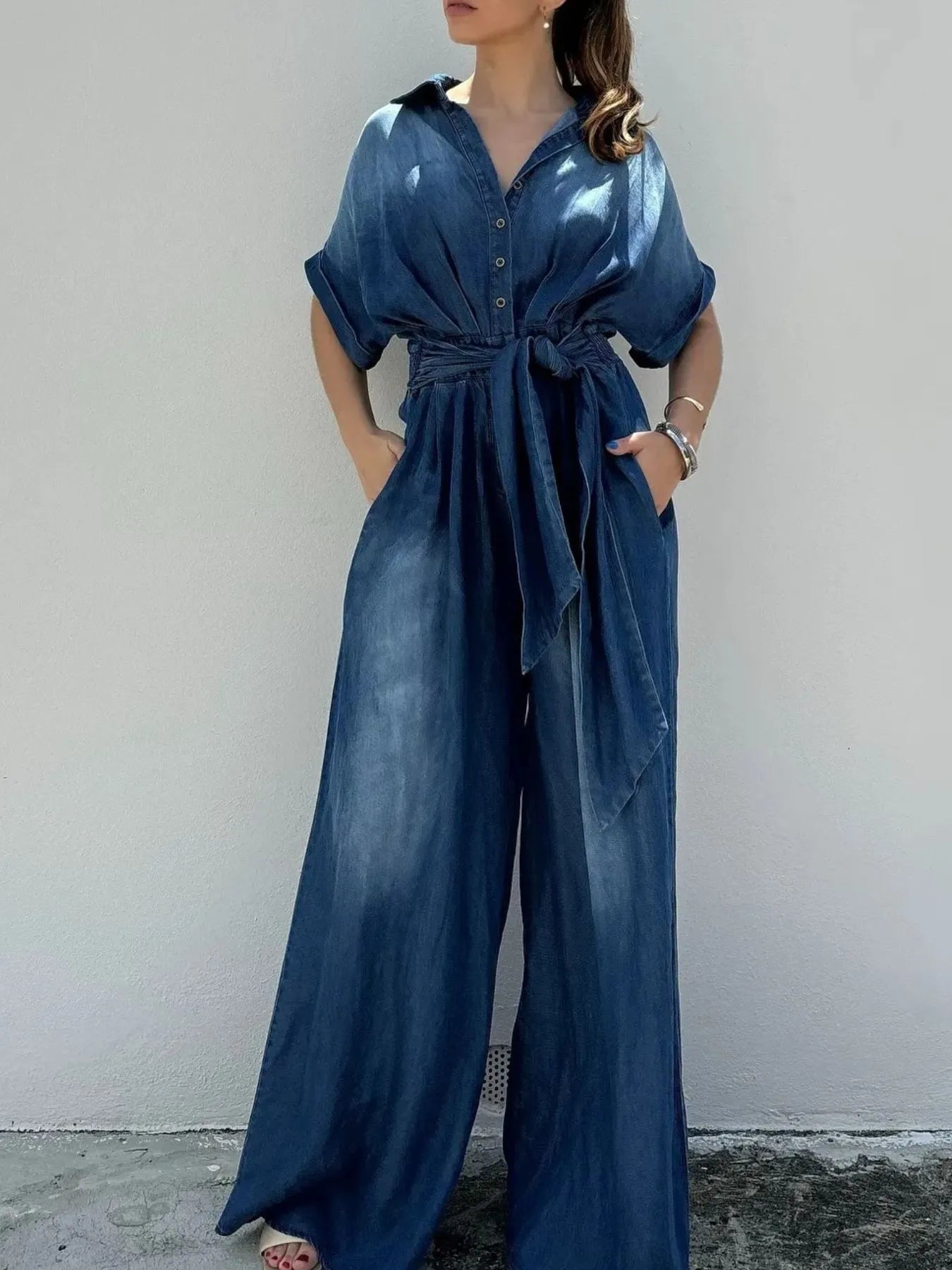 NEWYORKLISTED STYLE COLLECTION: Woman wearing a blue jumpsuit against a plain background
