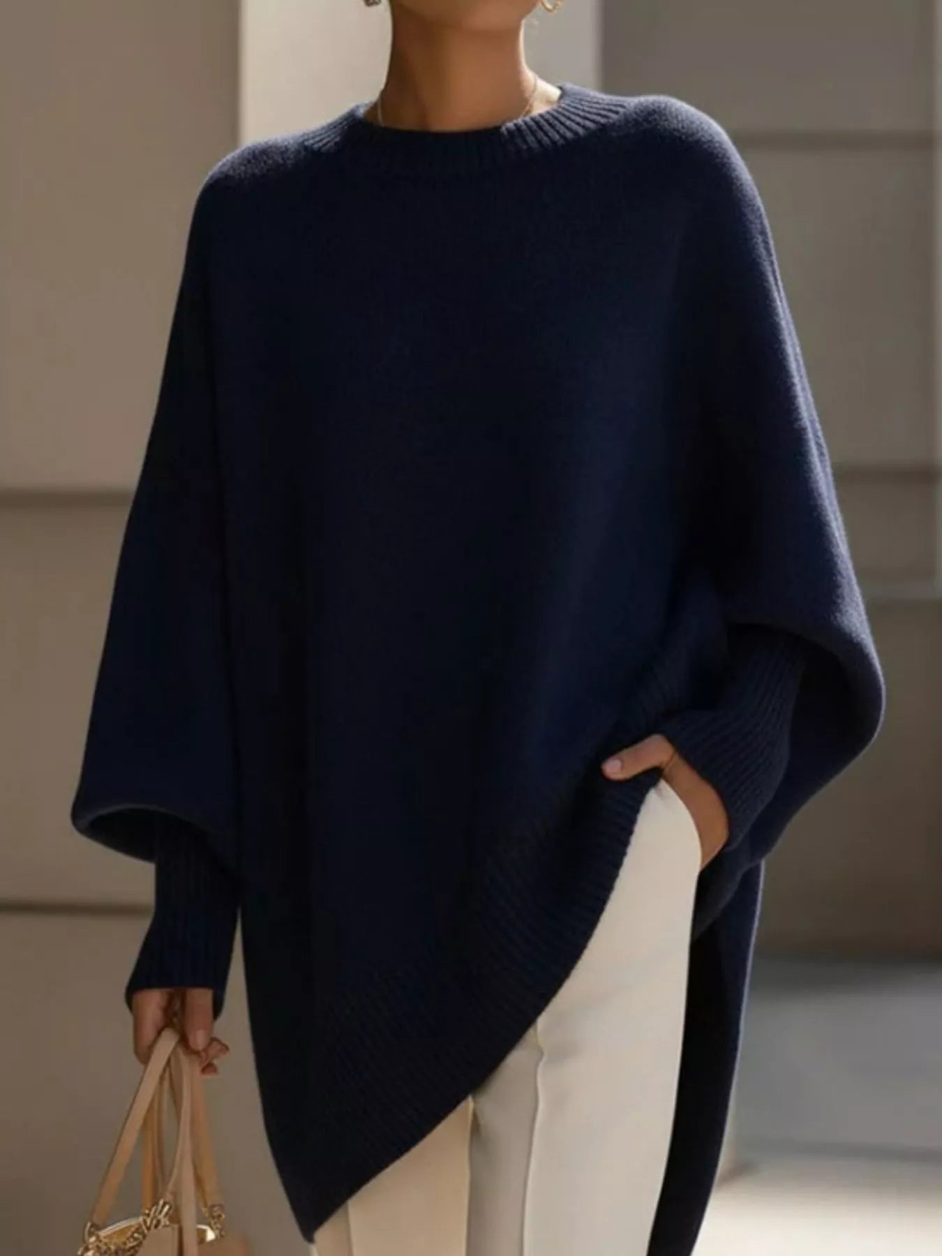 NEWYORKLISTED STYLE COLLECTION: Person wearing a navy blue poncho with a neutral background