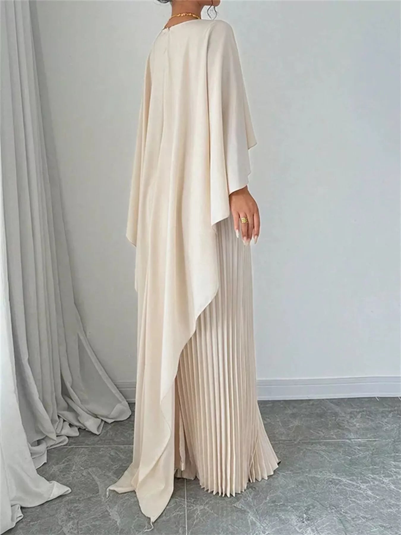 NEWYORKLISTED STYLE COLLECTION: Beige long dress with pleated skirt against a plain background