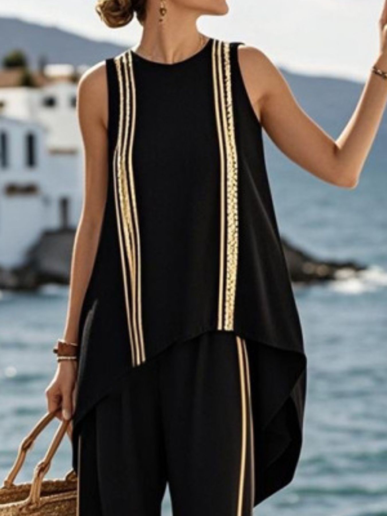 NEWYORKLISTED STYLE COLLECTION: Woman wearing a black sleeveless top with gold trim by the sea
