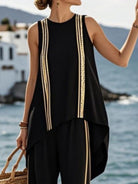 NEWYORKLISTED STYLE COLLECTION: Woman wearing a black sleeveless top with gold trim by the sea
