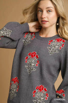 NEWYORKLISTED STYLE COLLECTION: Woman wearing a gray sweater with red floral patterns on a beige background