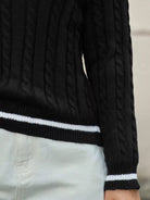 NEWYORKLISTED STYLE COLLECTION:  Black cable knit sweater with white trim on a neutral background