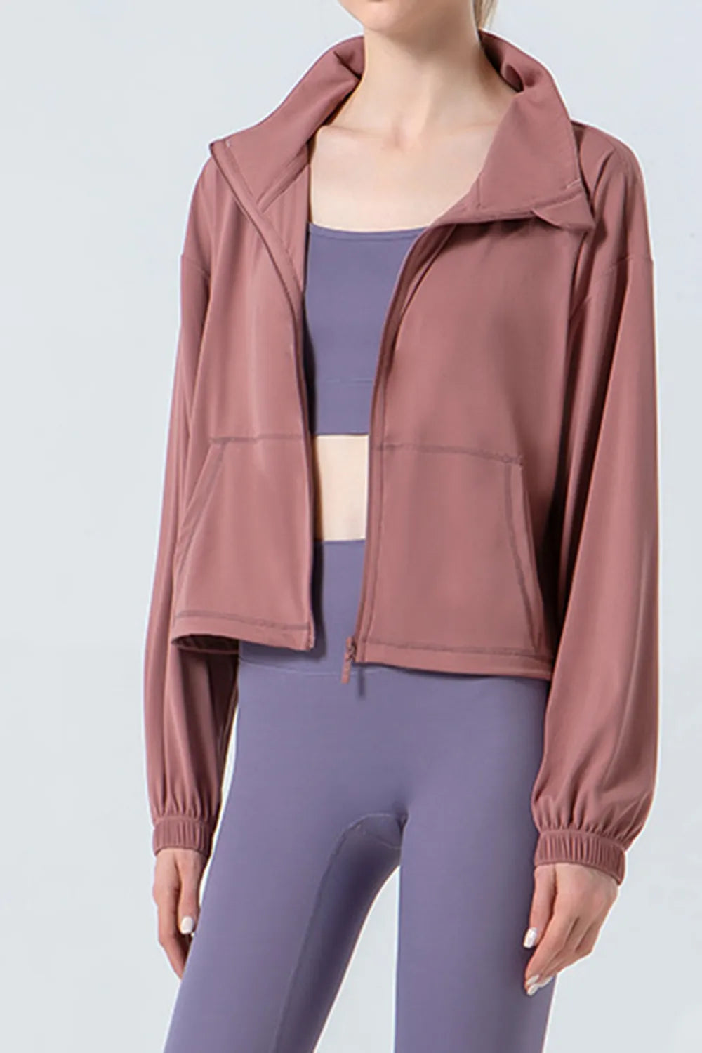 NEWYORKLISTED ACTIVEWEAR COLLECTION: Person wearing a mauve jacket over a purple athletic outfit on a light gray background