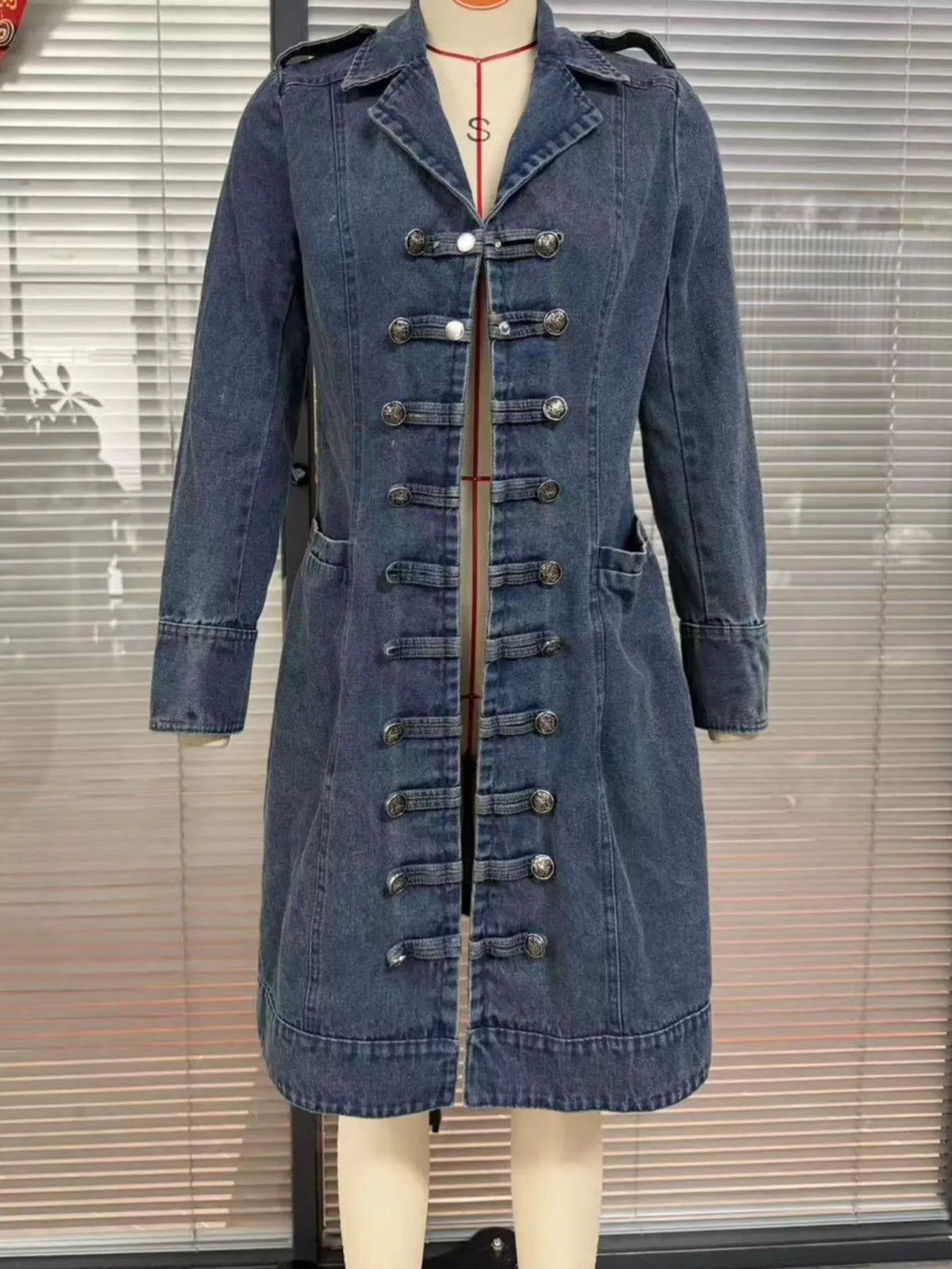 NEWYORKLISTED STYLE COLLECTION – Women's long blue denim military-style jacket featuring decorative gold buttons, structured collar, tailored silhouette, and long sleeves, styled with a white button-down shirt and blue jeans.
