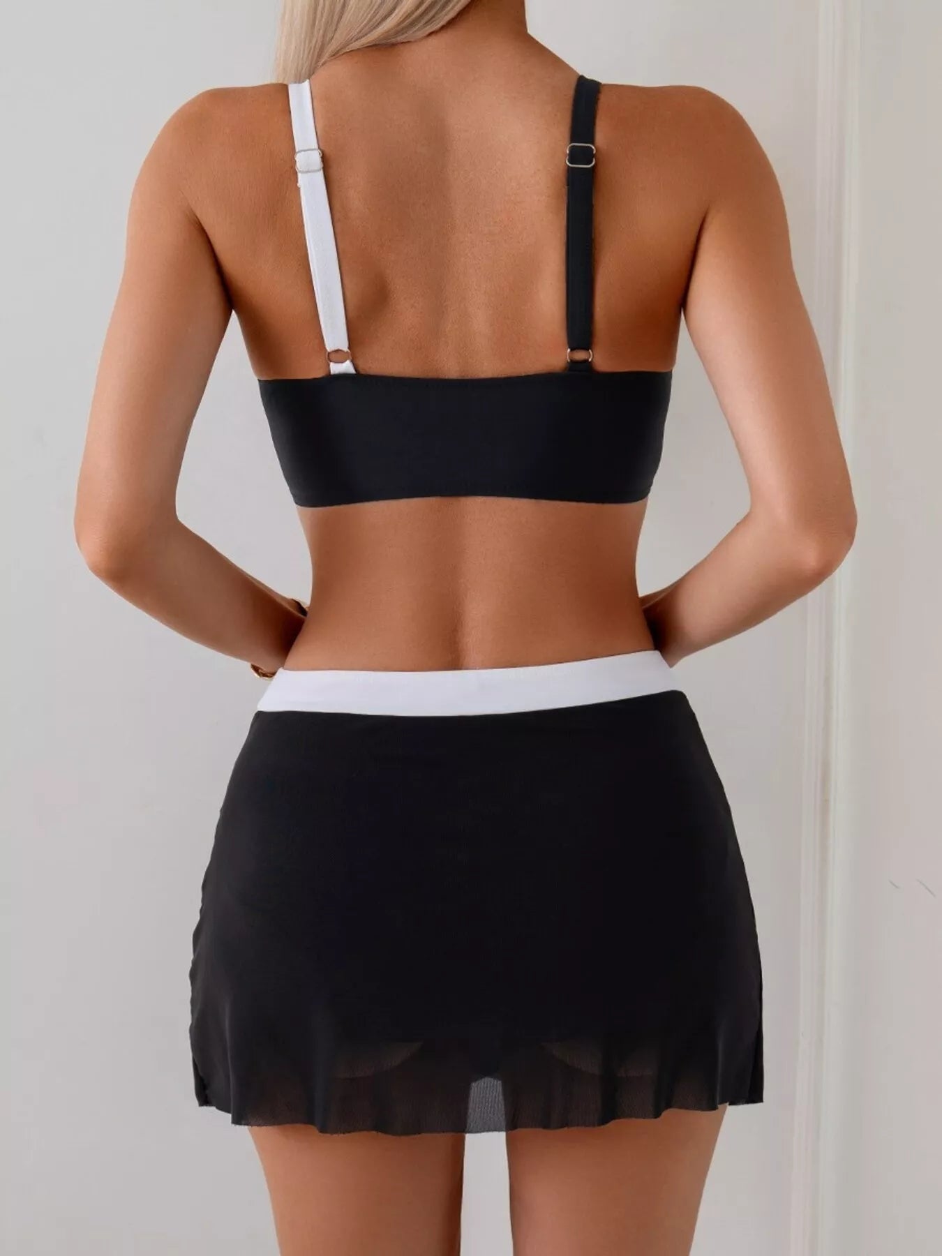 NEWYORKLISTED EDEN COLLECTION: Person wearing a black bikini top and black skirt against a plain background
