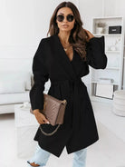 NEWYORKLISTED STYLE COLLECTION: Woman wearing a black coat and sunglasses in a modern living room.