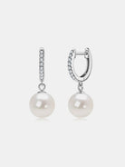 NYLD GLAMOUR COLLECTION by NEWYORKLISTED: Pair of pearl earrings with silver hooks on a light gray background