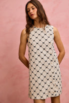 NEWYORKLISTED STYLE COLLECTION: Woman wearing a white dress with black pattern against a pink background