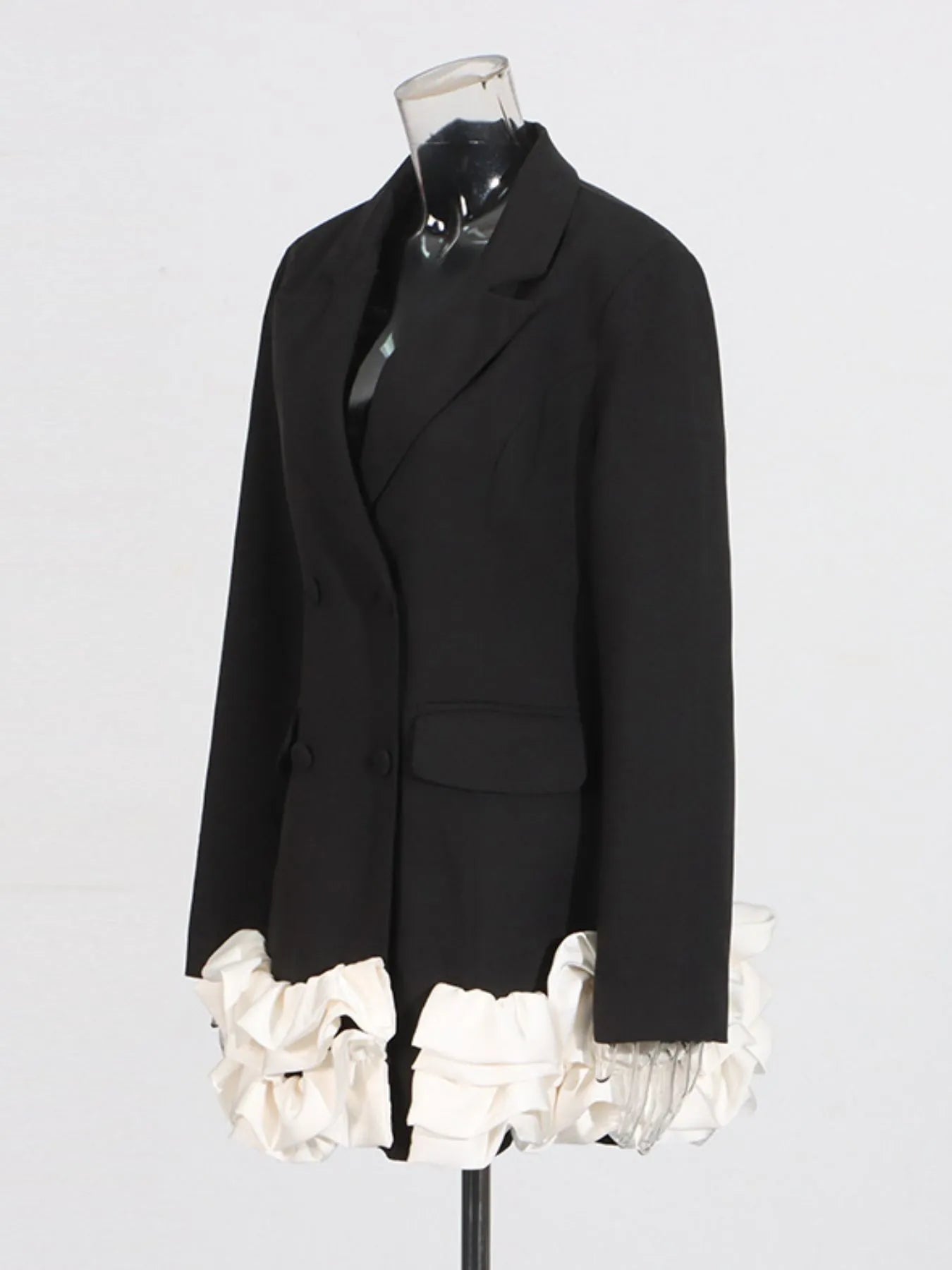 NEWYORKLISTED Runway Style: Black blazer with white ruffled hem on a mannequin against a light gray background