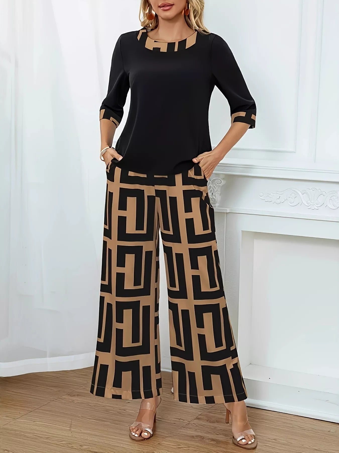 NEWYORKLISTED STYLE COLLECTION: Woman wearing a black top and tan colored patterned pants standing against a white wall.
