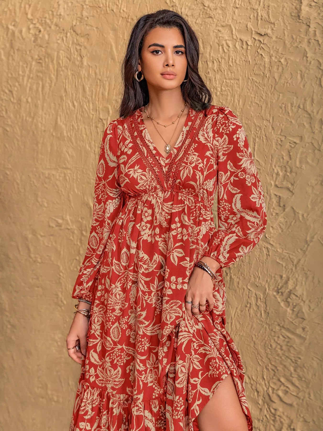 NEWYORKLISTED STYLE COLLECTION: Woman wearing a red floral dress against a textured beige wall