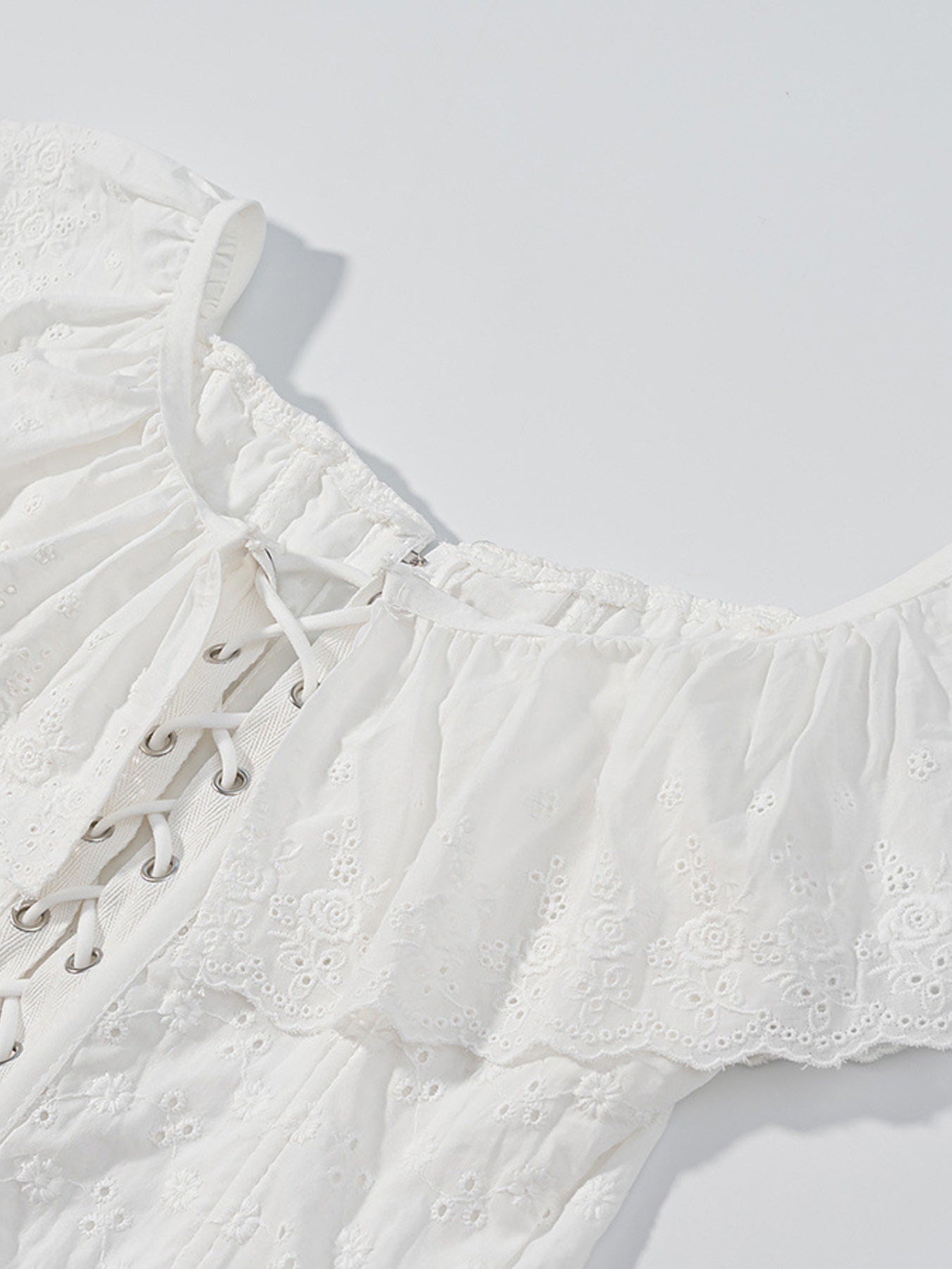 NEWYORKLISTED STYLE COLLECTION: White lace top with intricate detailing on a light gray background