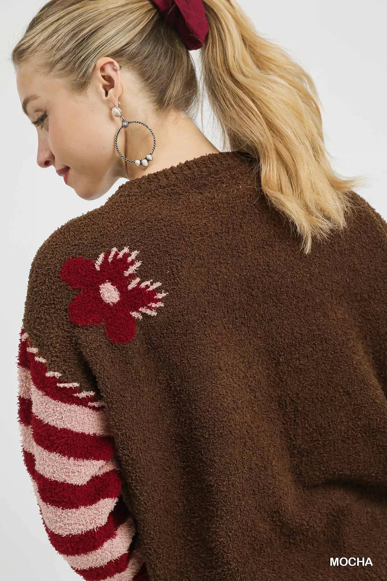 NEWYORKLISTED: Brown cardigan with red flower design on a plain background