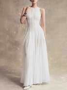 NEWYORKLISTED STYLE COLLECTION: Woman wearing a white dress against a textured beige wall