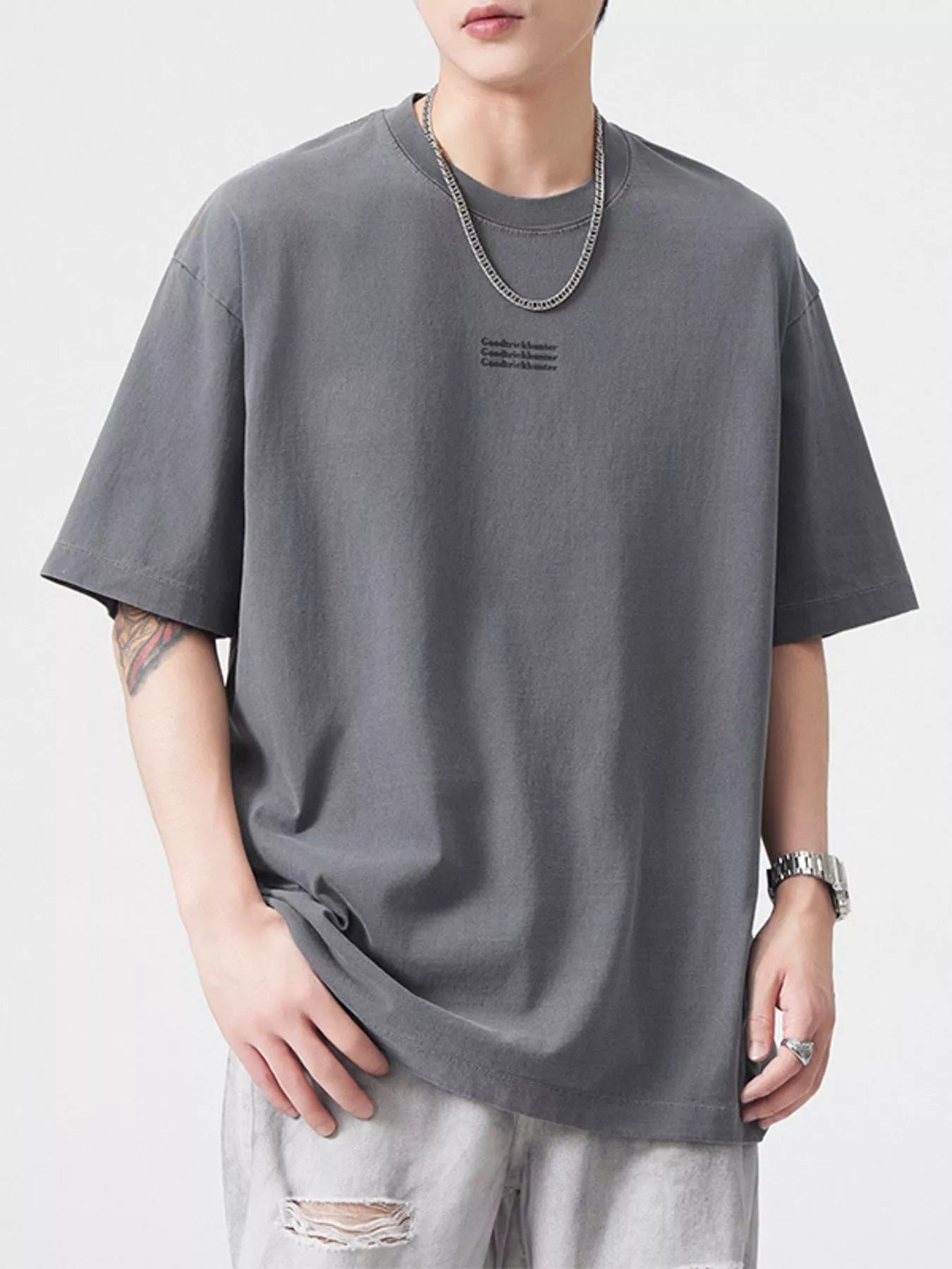 NEWYORKLISTED ATLAS MEN's COLLECTION: Person wearing a gray t-shirt with a small logo on a white background