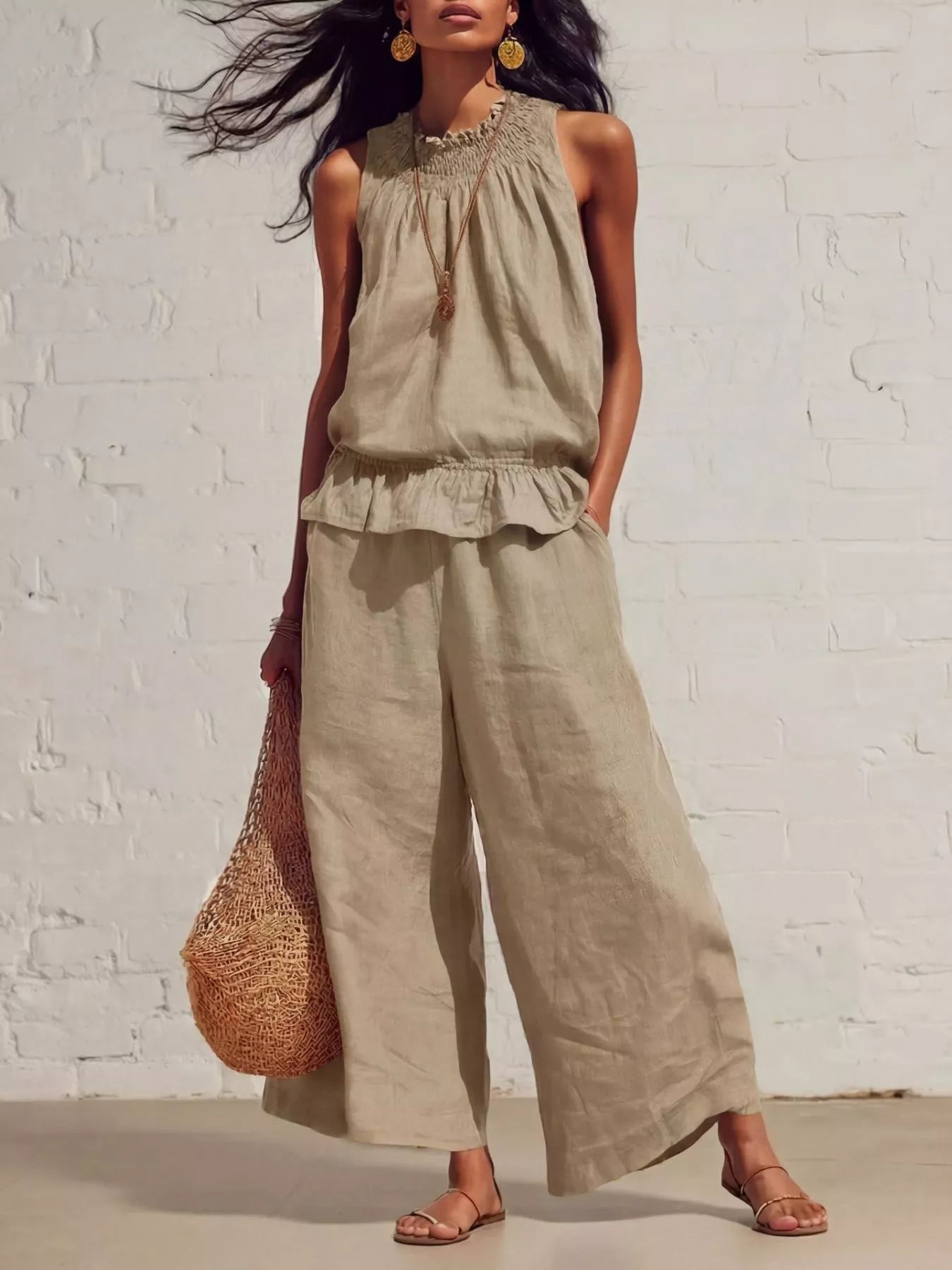 NEWYORKLISTED STYLE COLLECTION: Woman wearing a beige sleeveless top and wide-leg pants against a white brick wall.