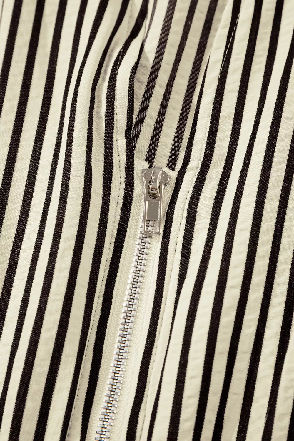 NEWYORKLISTED STYLE COLLECTION: Close-up of a black and white striped fabric with a zipper running vertically.