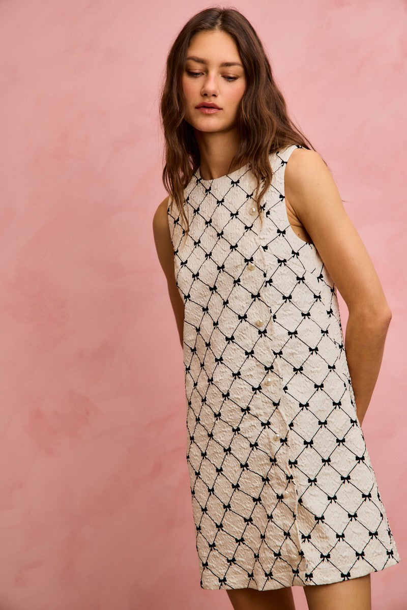 NEWYORKLISTED STYLE COLLECTION: Woman wearing a sleeveless dress with a geometric pattern against a pink background