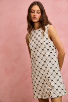 NEWYORKLISTED STYLE COLLECTION: Woman wearing a sleeveless dress with a geometric pattern against a pink background