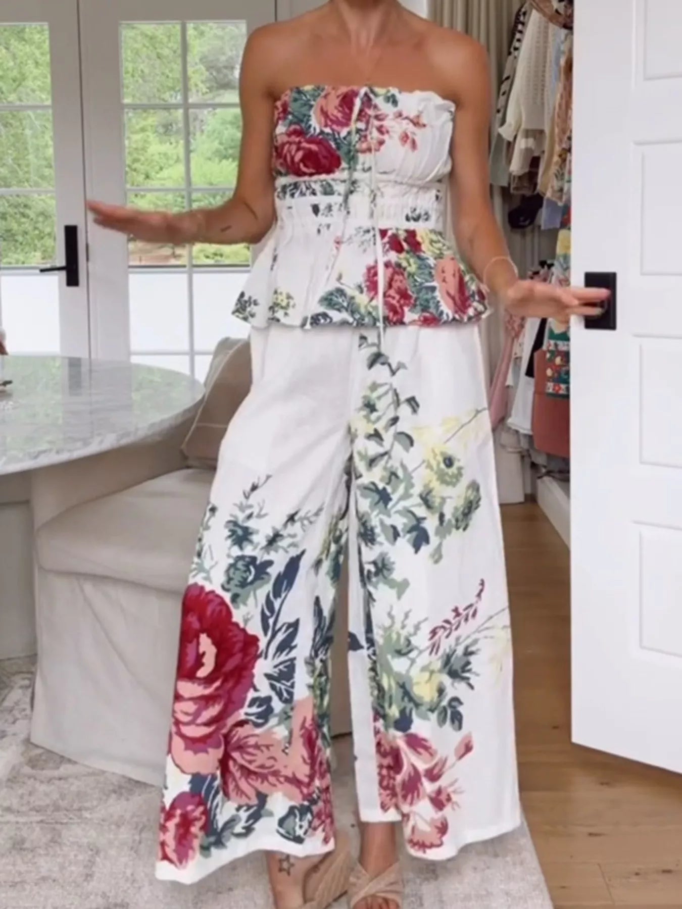 NEWYORKLISTED STYLE COLLECTION: Woman wearing a floral strapless top and wide-leg pants in a room with a white door and window.