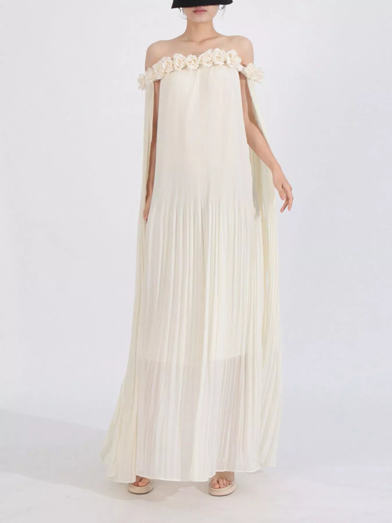 NEWYORKLISTED STYLE COLLECTION: Woman wearing a long, off-shoulder cream dress with floral details on a white background