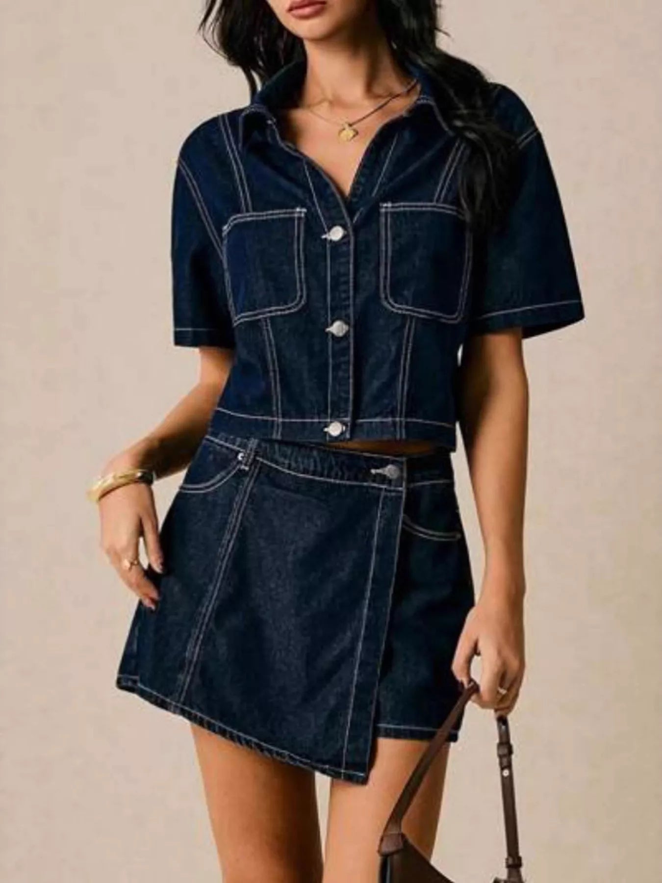 NEWYORKLISTED STYLE COLLECTION: Woman wearing a dark blue denim outfit with a beige background