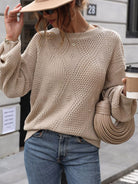 NEWYORKLISTED STYLE COLLECTION: Woman wearing a beige knit sweater and blue jeans, holding a beige handbag and a coffee cup. 