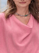 NEWYORKLISTED STYLE COLLECTION: Close-up of a person wearing a pink garment with a necklace featuring green gemstones.