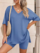 NEWYORKLISTED COMFORT COLLECTION: Woman wearing a blue outfit with a straw bag, standing against a neutral background.