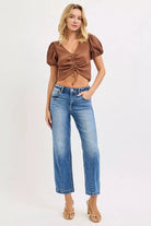 NEWYORKLISTED DENIM COLLECTION: Woman wearing a brown top and blue jeans on a white background