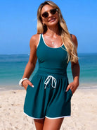 NEWYORKLISTED STYLE COLLECTION: Woman in a teal dress standing on a beach with ocean in the background